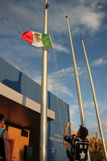 A protester raises the Mexican flag outside Aurora's immigrant detention center.